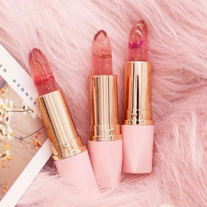 Three lipsticks with gold caps on a pink fluffy surface