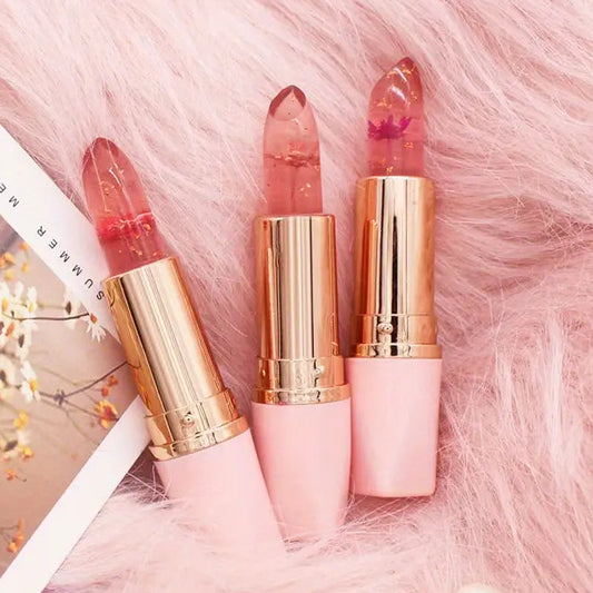 Three lipsticks with gold caps on a pink fluffy surface